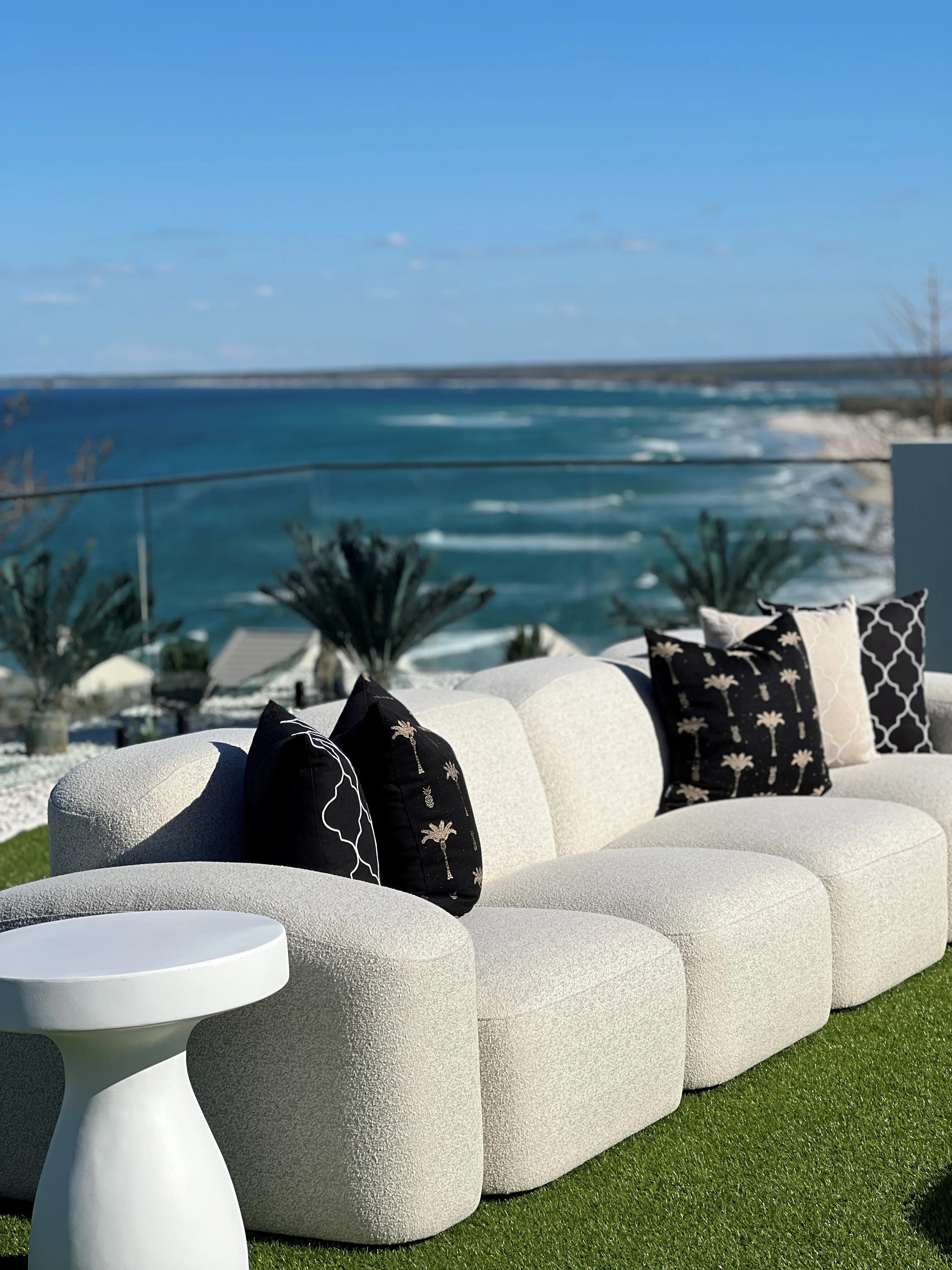 Outdoor bouclé sofa detail with black palm-print cushions overlooking Kings Beach
